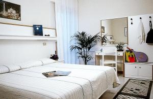 a white bedroom with a white bed and a desk at Hotel Nelson in Lido di Jesolo