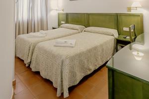 
a hotel room with two beds and a desk at Lantana Garden in Pilas
