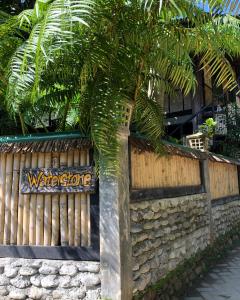 ein Zaun mit einem Willkommensschild neben einem Baum in der Unterkunft Waterstone Guesthouse in Bukit Lawang