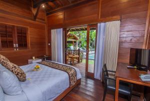 a bedroom with a bed and a desk and a television at Batu Agung Villa Ubud in Ubud