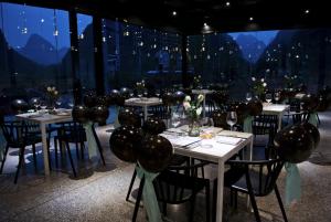 a dining room with tables and chairs with lights at SIXX Hotel Yangshuo in Yangshuo