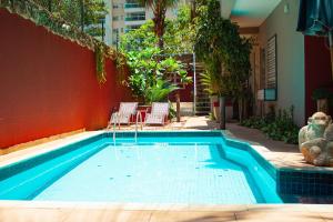 a swimming pool with chairs and a red wall at Vila Jabutis in Guarujá