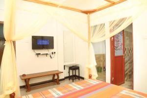 une chambre avec un lit et une télévision au mur dans l'établissement Global Lake Villa Hikkaduwa, à Hikkaduwa