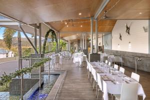 a restaurant with white tables and white chairs at Club Wyndham Airlie Beach in Airlie Beach