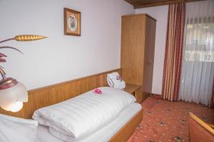 a bedroom with a bed with white sheets and pink flowers at Hotel Sonne in Wagrain