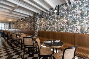 a row of tables and chairs in a restaurant with a floral wall at Elmina Hotel Jaffa in Tel Aviv