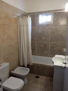 a bathroom with a toilet and a sink and a tub at El chalecito de Marta (PH) in Necochea