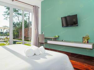1 dormitorio con 1 cama y TV en la pared en Ylang Garden Villa, en Hoi An