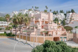 ein rosafarbenes Apartmenthaus mit Palmen und Häusern in der Unterkunft Apartamento Ibn sadi14 in Nerja