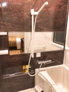 La salle de bains est pourvue d'un tuyau blanc suspendu au mur. dans l'établissement Business Hotel Crescent, à Tokyo