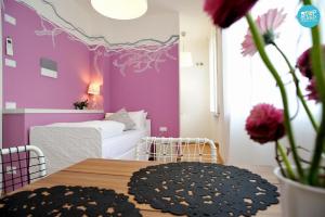 1 dormitorio con paredes de color púrpura, mesa y cama en Stop & Sleep Udine Fronte Ospedale Civile en Udine