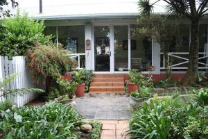une terrasse couverte à l'avant d'une maison ornée de plantes dans l'établissement Panda's Guest Cottages, à Kaapsehoop