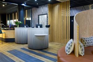 a lobby with a reception desk and a couch at ibis Styles Massy Opéra in Massy