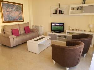 a living room with a couch and a tv and chairs at Jaen Home in Jaén