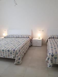 twee bedden in een witte kamer met twee lampen bij Cala Blu Residence con piscina-Centralissimo Lido di Jesolo in Lido di Jesolo