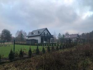 una casa detrás de una valla en un campo en Lakehouse Nakielno en Wałcz