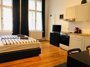a room with a bed and a kitchen with windows at Modernes Apartment am Viktoria Luise Platz in Berlin