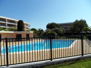 a fence around a swimming pool in front of a building at Appartement 3 pieces, refait a neuf, haut standing, piscine, mer a pieds in Antibes