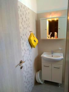 a bathroom with a sink and a yellow bag on the wall at Twins Studios in Benitses