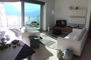 uma sala de estar com mobiliário branco e uma grande janela em Luci sul Lago - A Real Paradise em Perledo