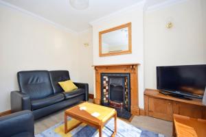 a living room with a black leather couch and a fireplace at Church Cottage, Worthing in Worthing