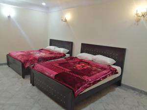 Star Hotel Lahore في لاهور: غرفة نوم بسريرين مع بطانيات ومخدات حمراء