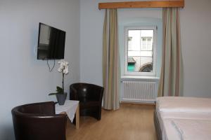 a hotel room with a bed and a tv and a chair at Gasthof Goldene Traube in Golling an der Salzach