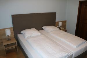 a large bed with white sheets and pillows on it at Gasthof Goldene Traube in Golling an der Salzach