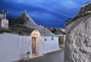 a white building with a roof with a door at Trulli Holiday Albergo Diffuso in Alberobello