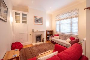 a living room with a red couch and a fireplace at Polly's - Aldeburgh Coastal Cottages in Aldeburgh