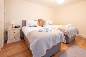 two beds with white sheets in a bedroom at Polly's - Aldeburgh Coastal Cottages in Aldeburgh