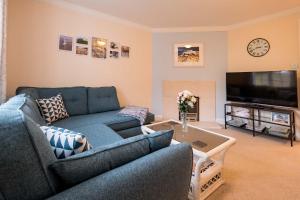 a living room with a blue couch and a tv at Pinky Cottage in Aldeburgh