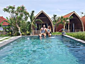 Ein Mann und eine Frau sitzen im Pool in der Unterkunft Umma Bali Menjangan Retreat in Banyuwedang