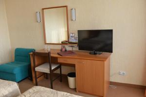 Habitación con escritorio, TV y silla. en Hotel Bellevue, en Skopje