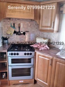 a kitchen with a white stove and wooden cabinets at Serenity Seton Sands in Longniddry
