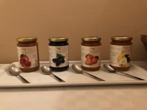 cuatro frascos de mermelada y cucharas en una bandeja en Villa Carolea, en Acireale