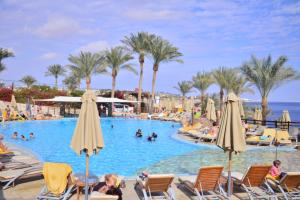 een zwembad in een resort met mensen in stoelen en parasols bij Xperience Sea Breeze Resort in Sharm El Sheikh