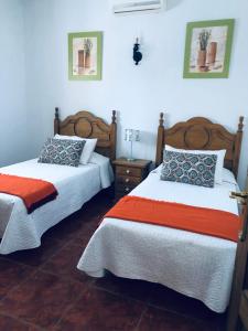 フエンカリエンテ・デ・ラ・パルマにあるApartamento la eraの白とオレンジのシーツが備わる客室のベッド2台