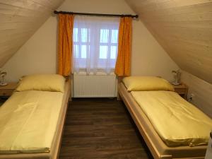 2 Betten in einem Dachzimmer mit Fenster in der Unterkunft Apartman Herman in Rudník