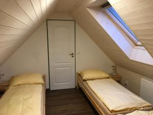 2 Betten in einem Dachzimmer mit Fenster in der Unterkunft Apartman Herman in Rudník