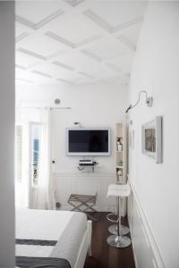 a white bedroom with a bed and a tv on the wall at Casa San Vito in Monopoli