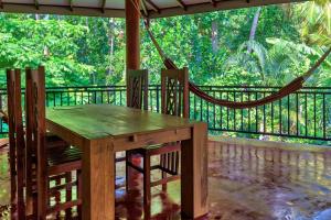 einen Holztisch und Stühle auf einer Veranda mit einer Hängematte in der Unterkunft Julia Safari Inn in Tissamaharama