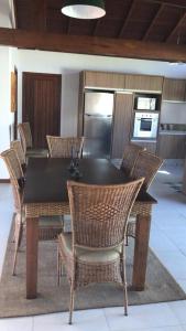 a dining room table with chairs and a kitchen at Casa na praia , Ar c, pisc,bosque , dunas e lagoa in Florianópolis