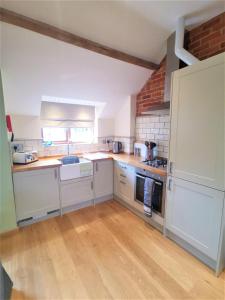 - une cuisine avec des appareils blancs et un mur en briques dans l'établissement Blashford Manor Farmhouse - New Forest Cottage, à Ringwood 9 autres photos