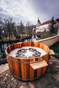 a large wooden tub with snow in it next to a river at Ultra premium apartments in Český Krumlov