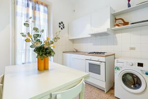 een witte keuken met een vaas met bloemen op een aanrecht bij Loreto Courtyard Apartment in Milaan