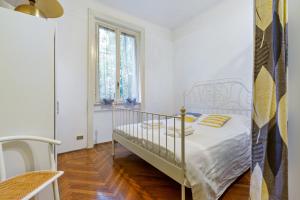 a white bedroom with a bed and a window at Loreto Courtyard Apartment in Milan