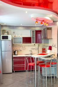 eine Küche mit roten Schränken und einem Tisch mit roten Stühlen in der Unterkunft Люкс студия 1 комнатная,в центральном районе города in Mykolajiw
