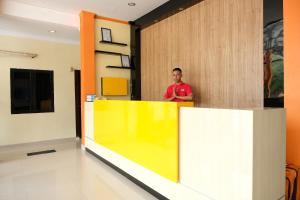 a man standing behind a yellow counter in a room at OYO 1149 Hotel Mustika in Tanjungpandan