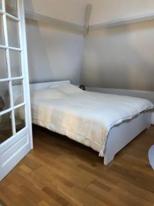 een slaapkamer met een wit bed en een houten vloer bij Charmante maison cœur de ville La Gare des vacances in Deauville